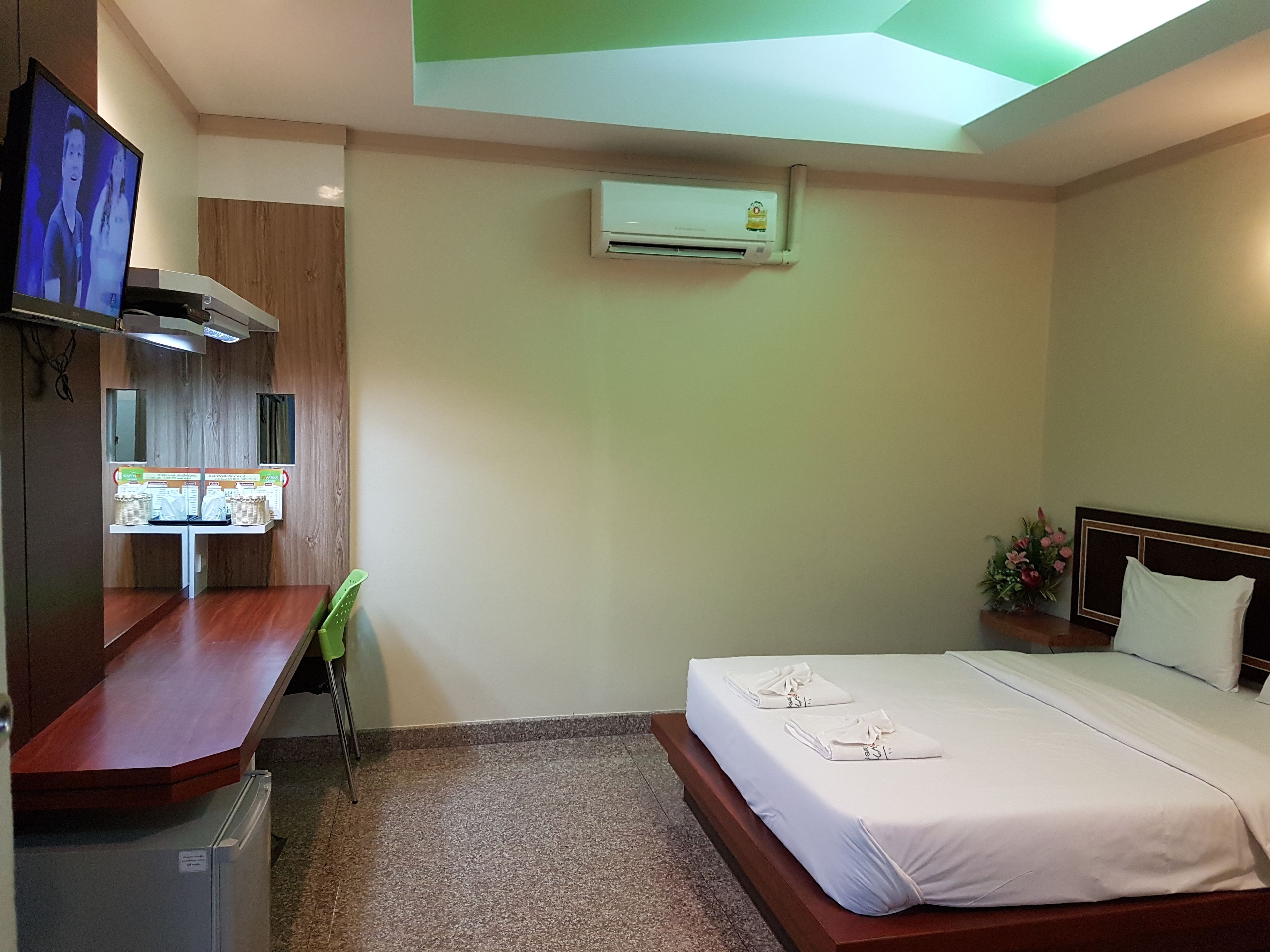 Una habitación de hotel con cama, escritorio, televisión y aire acondicionado.