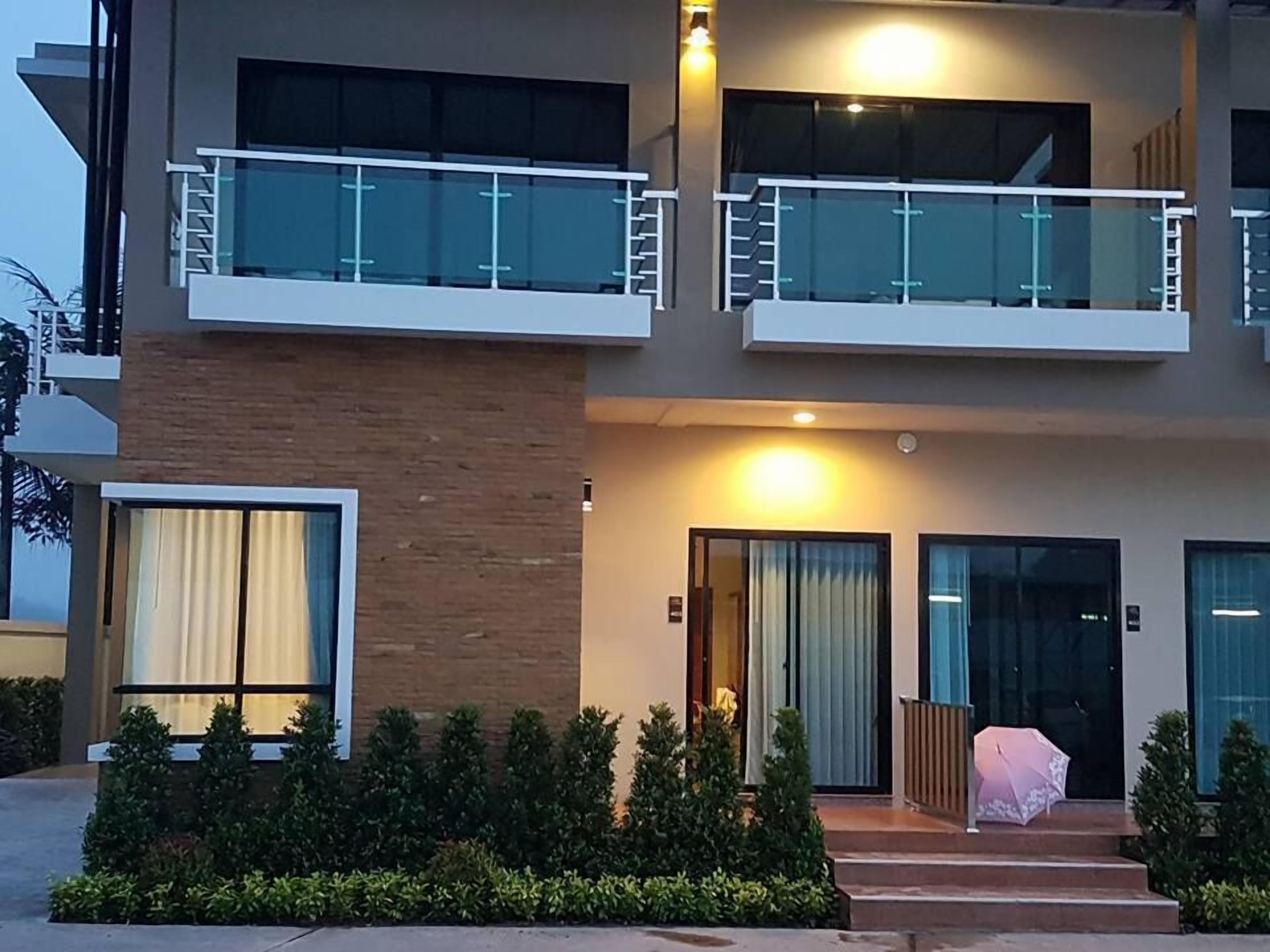 A modern two-story building with a balcony, large windows, and a well-lit entrance.