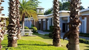 A modern building with a central tower, surrounded by palm trees and well-maintained lawns. - Smile Resort Thungsong (Thung Song)