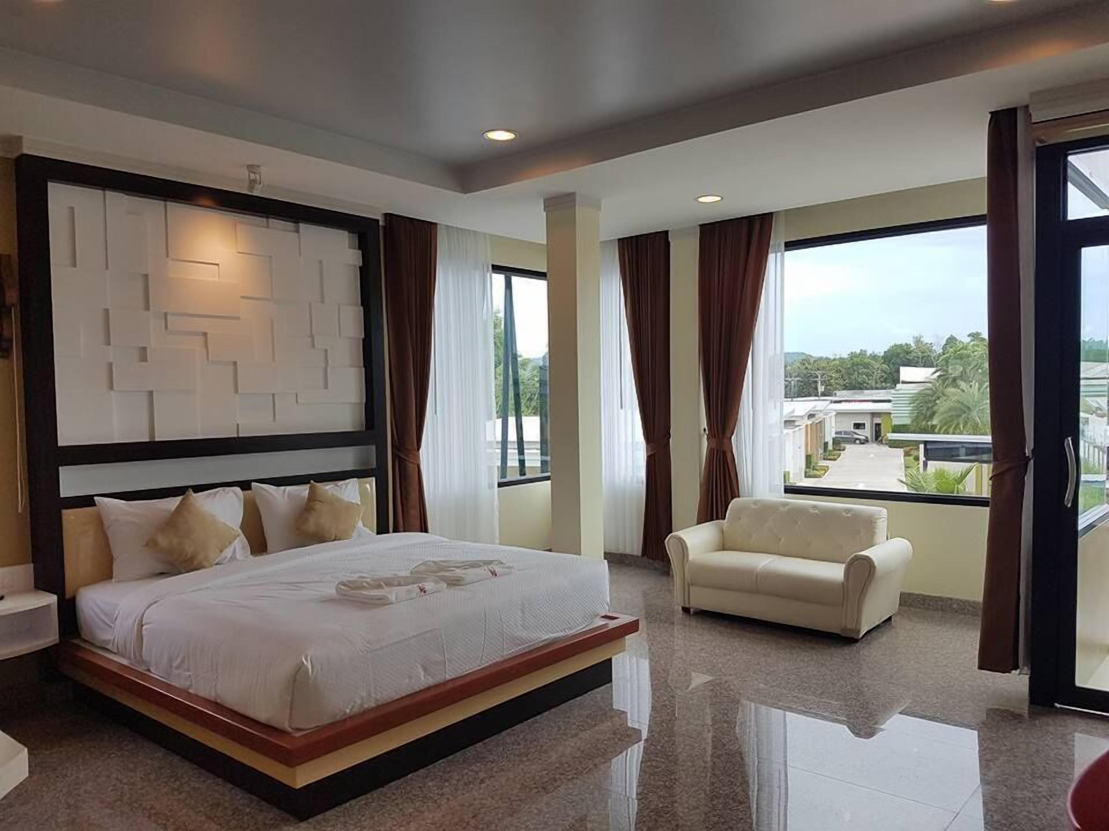 A modern hotel room with a large bed, a sofa, and a view of the city.