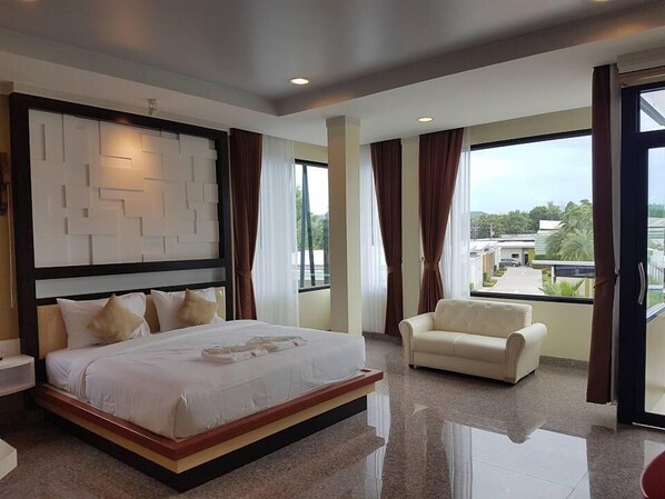 A modern hotel room with a large bed, a sofa, and a view of the city.