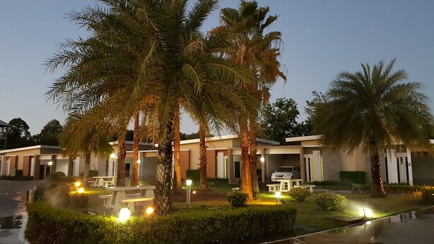 A hotel with multiple rooms, palm trees, and outdoor lighting. - Smile Resort Thungsong (Thung Song)