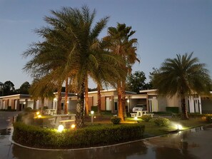Een hotel met meerdere kamers, palmbomen en buitenverlichting.