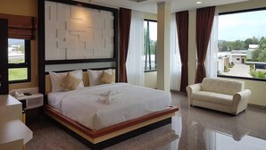 A modern hotel room with a large bed, a sofa, a desk, and a view of the outside. - Smile Resort Thungsong (Thung Song)