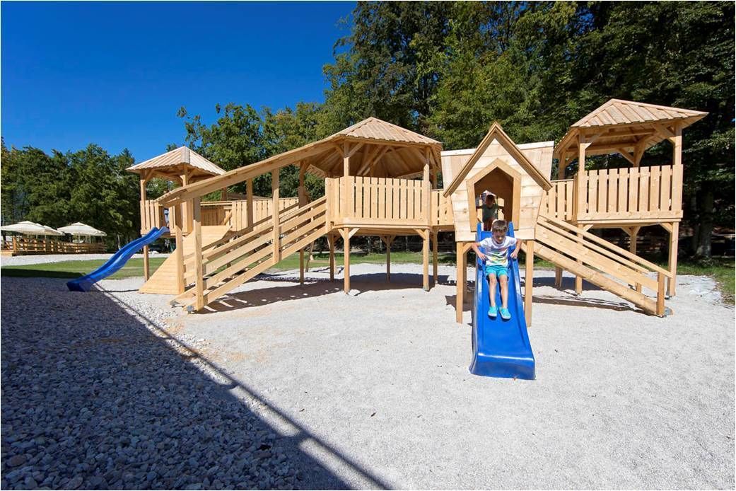 A wooden playground with a slide and climbing structures.