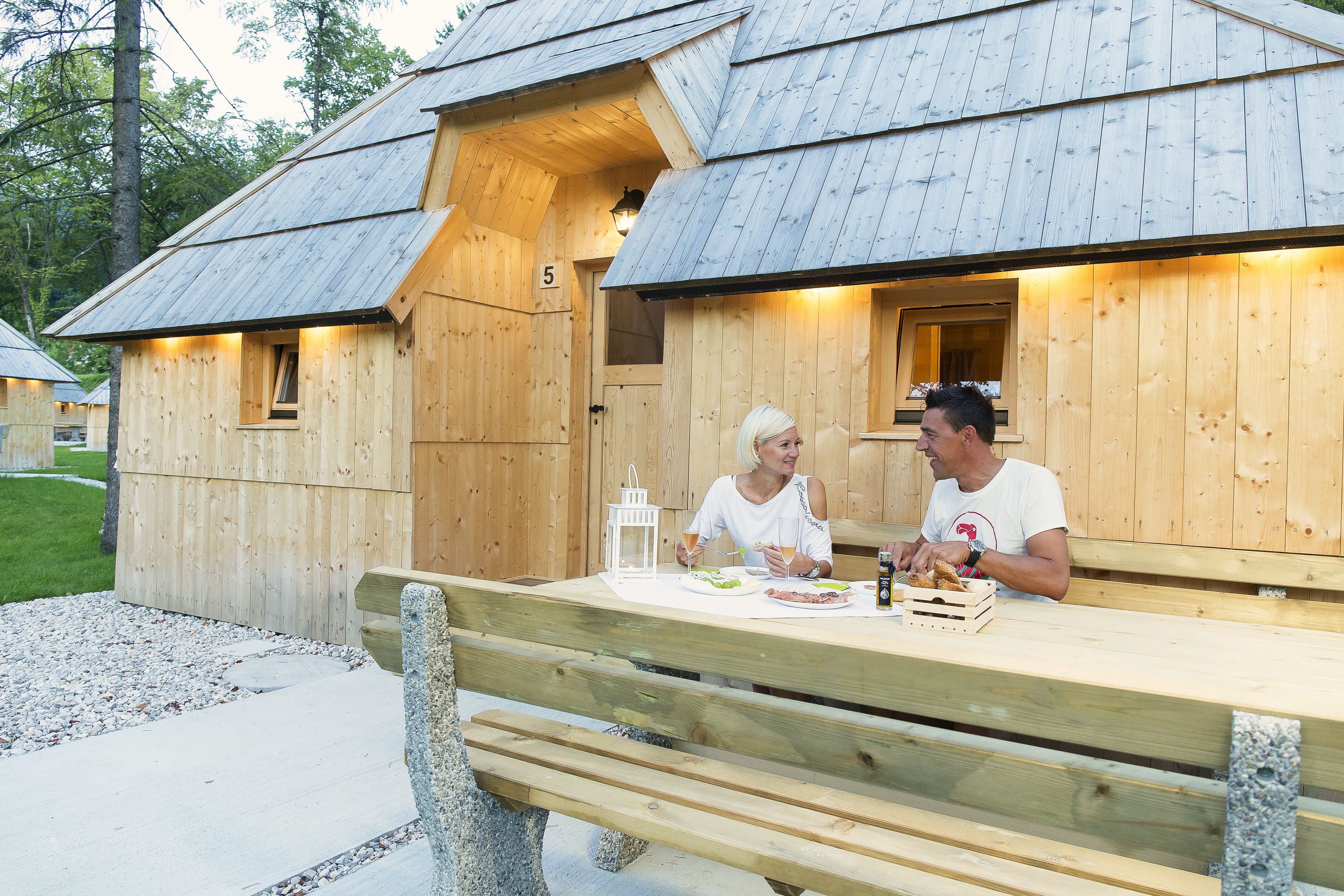 A wooden cabin with a bench and a table where two people are dining.
