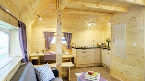 A cozy cabin interior with a wooden interior, a sofa, a dining table, and a kitchen area. - Slovenia Eco Resort (Kamnik)