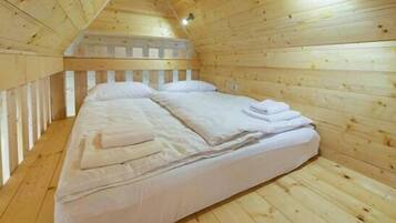 Une pièce de cabane en bois avec un lit simple, des murs en bois et un plafond en pente.