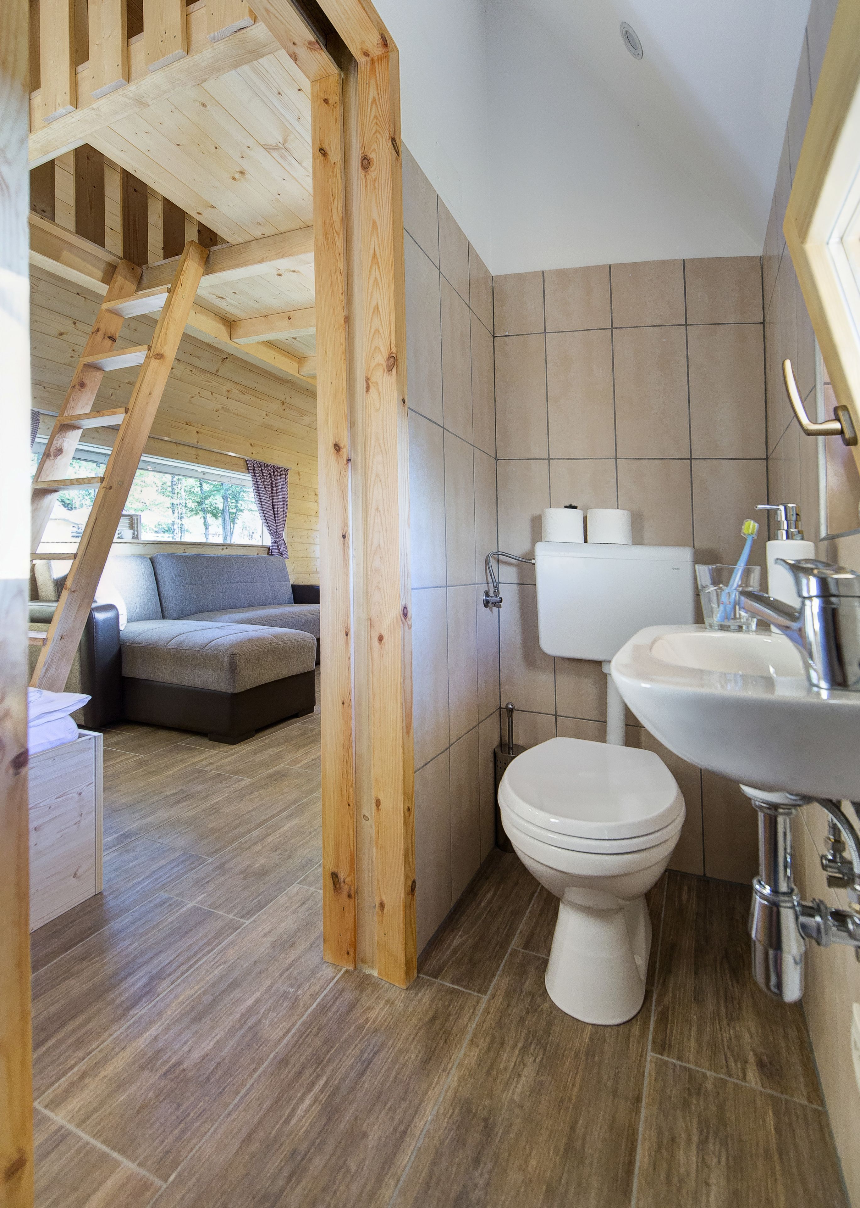 A modern bathroom with a toilet, sink, and wooden staircase.