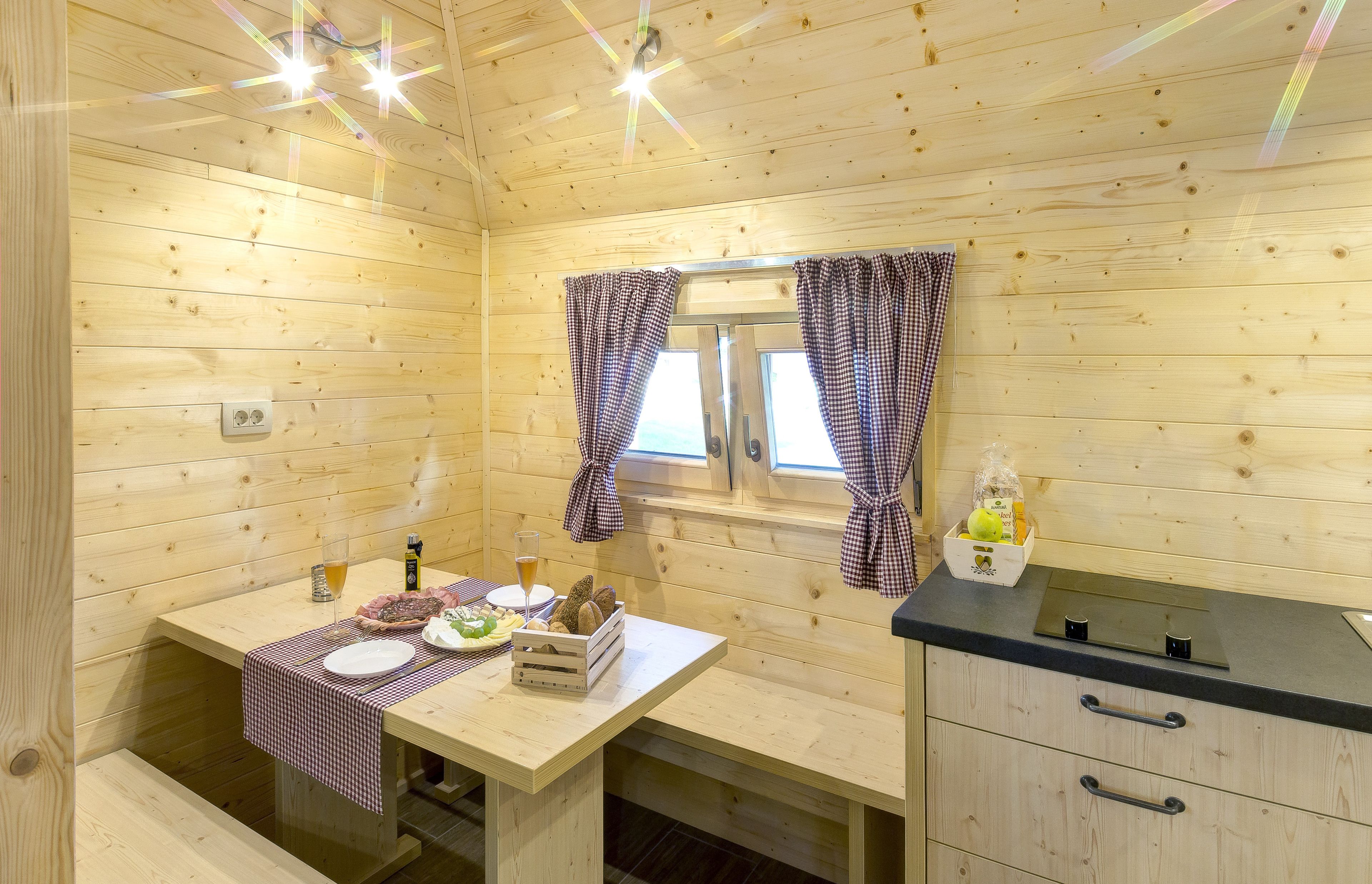 A wooden cabin with a dining table set with plates, glasses, and a basket of bread.