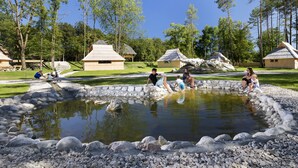 A pond surrounded by rocks, with people near the water. - Slovenia Eco Resort (Kamnik)
