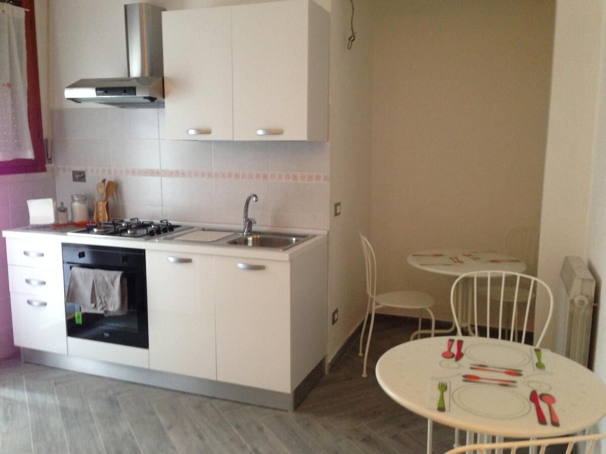 A compact kitchen with a stove, sink, and oven, adjacent to a dining area with a small table and chairs.