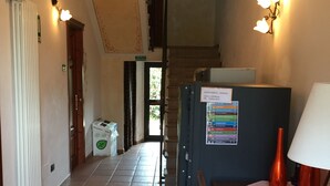 A hallway with a radiator, a table with a vase and a plate, and a staircase in the background. - La Locanda di Giorgia (Pisa)
