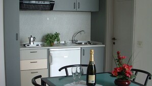 Cozinha compacta com armários cinza, pia e área de refeições com mesa e cadeiras.