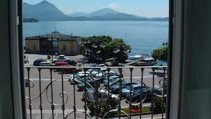 Vista de um estacionamento com carros em primeiro plano, um corpo d'água e montanhas ao fundo.
