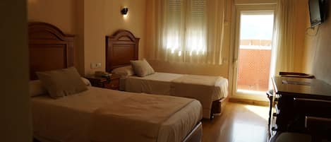A hotel room with two beds, a desk, and a television.