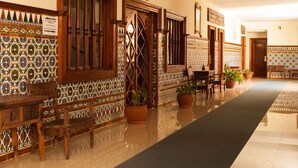 A hallway with patterned tiles, wooden furniture, and potted plants.