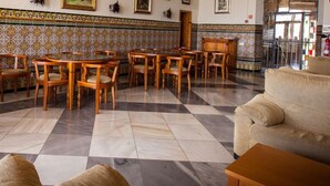 A spacious lobby with a checkered floor, wooden furniture, and tiled walls.
