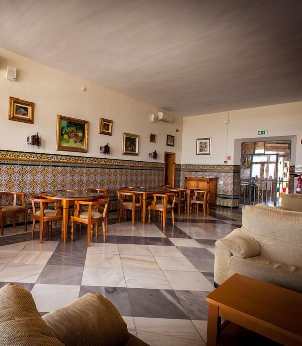 A spacious lobby with a checkered floor, wooden furniture, and tiled walls.
