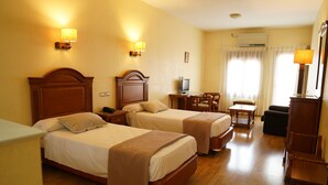 A hotel room with two beds, a desk, a chair, and a TV.
