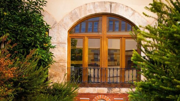A stone pathway leading to a building with a large arched window and a brick wall.