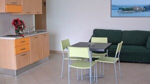 A compact living space with a kitchenette, a dining area with a table and chairs, and a green sofa. - Residence Tre Ponti (Verbania)