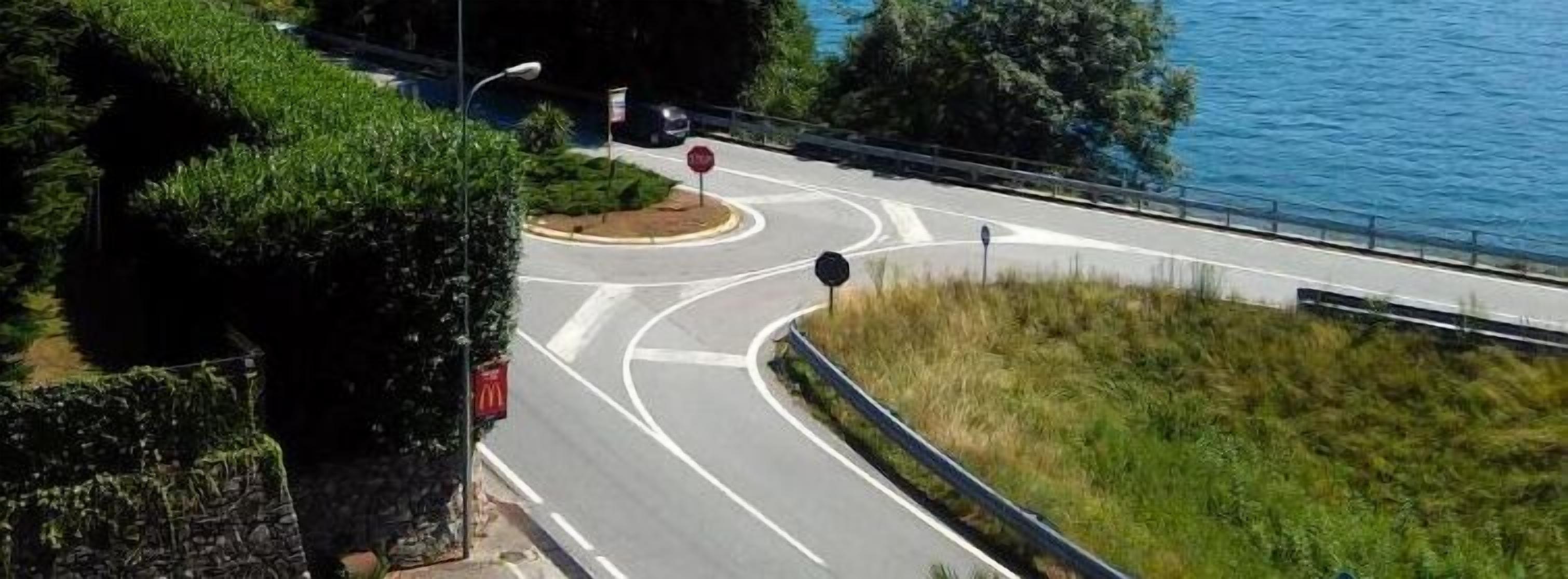 Eine Kreuzung mit Stoppschild, McDonald's Schild und Schutzplanke neben einem Gewässer.