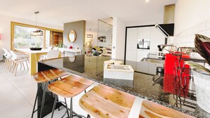 Una cocina moderna con una isla central, taburetes de bar y un comedor con sillas y una mesa.