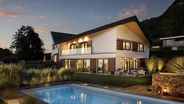 Una casa moderna de dos pisos con piscina, ventanas amplias y un jardín bien cuidado.
