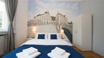 Habitación de hotel con cama, armario, mesita de noche y un mural de un puente y edificios.