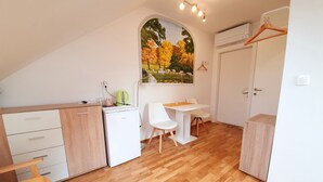 Una habitación compacta con kitchenette, comedor y cama.