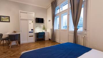 A hotel room with a bed, a desk, a chair, a television, and a window with curtains.