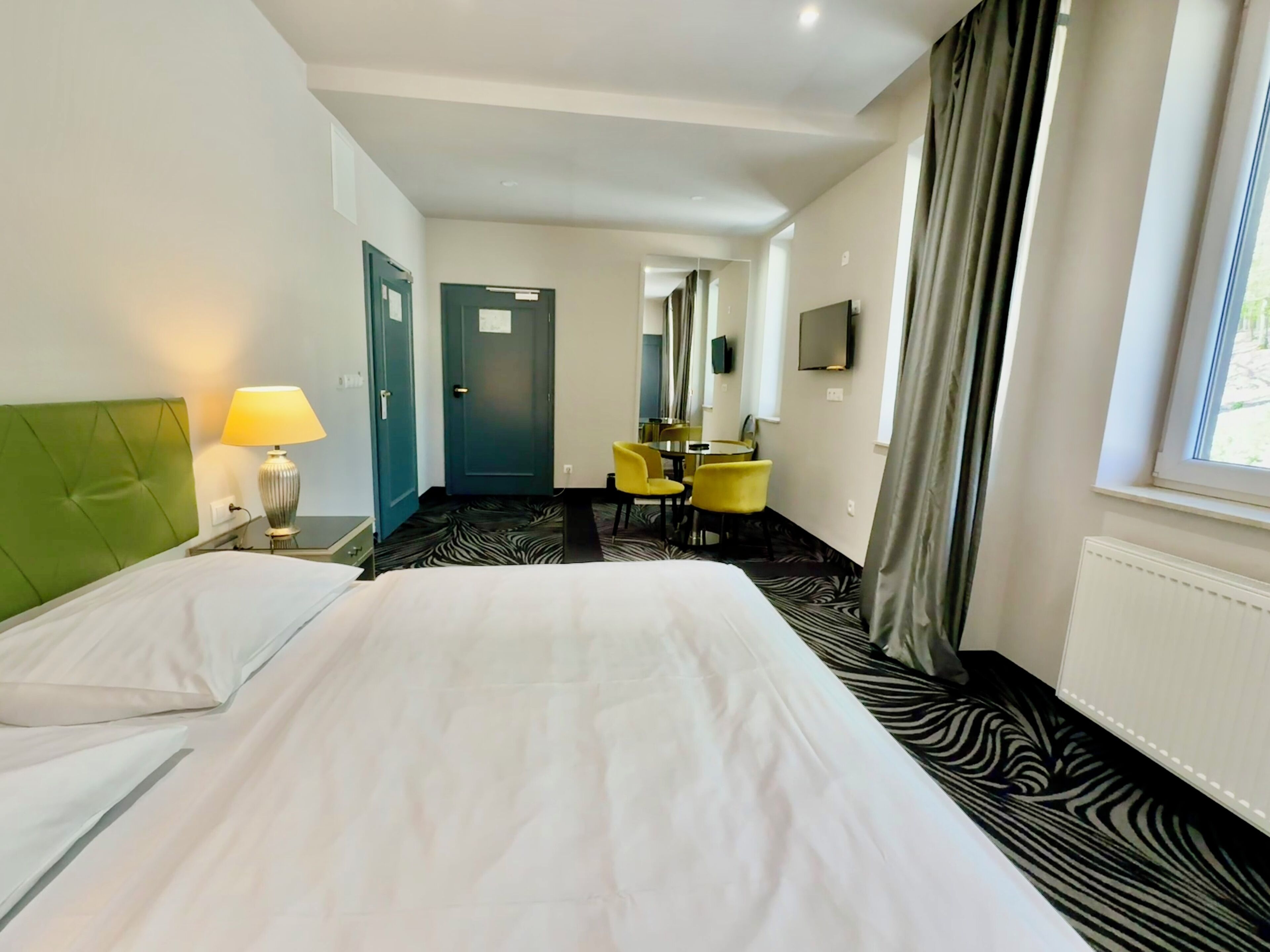 Ein Hotelzimmer mit einem Bett, einem Schreibtisch, einem Stuhl, einem Fernseher und einem Fenster.