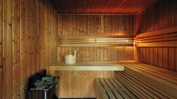 A wooden sauna with benches, a bench heater, and a trash bin.