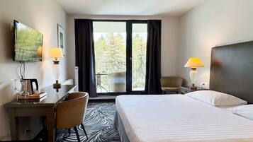 Een hotelkamer met een bed, bureau, stoel en uitzicht door het raam.