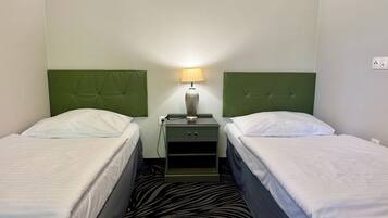Een hotelkamer met twee bedden, een nachtkastje met een lamp en een karpet met zebraprint.