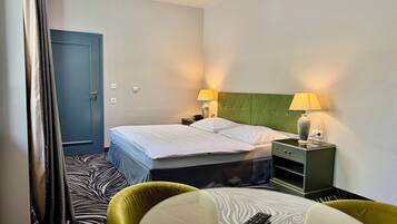 A hotel room with a bed, two bedside lamps, a nightstand, a table, and two chairs.