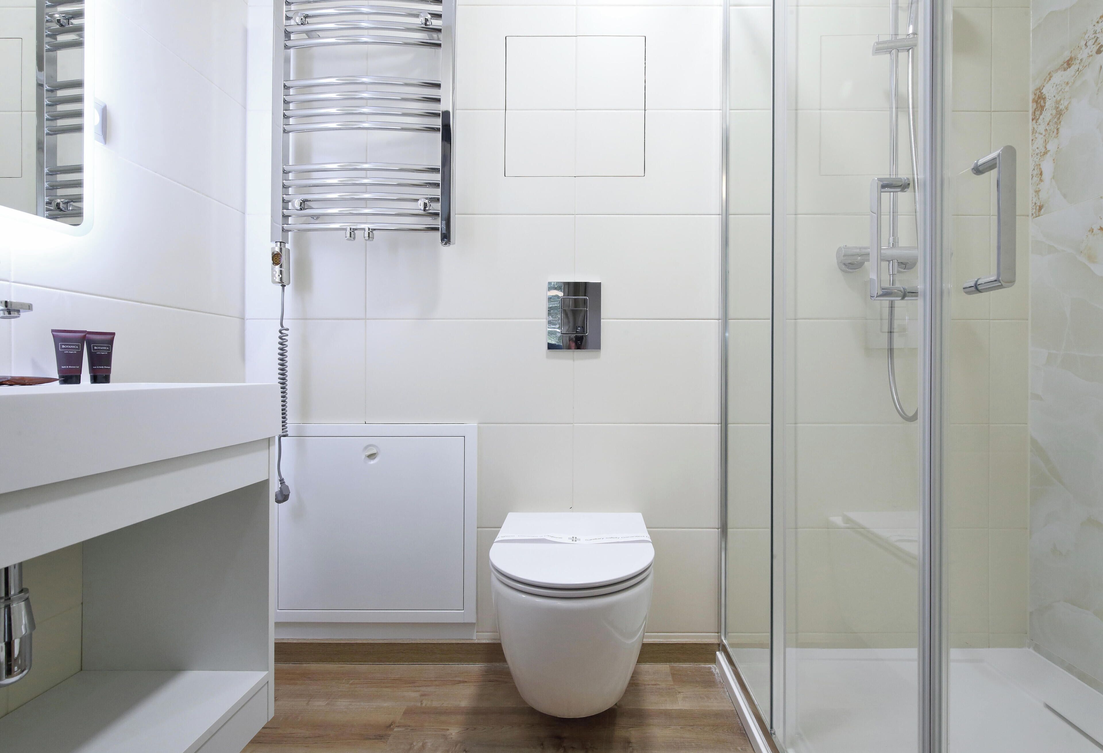 Un baño moderno con inodoro, ducha y zona de ducha con mampara de vidrio.