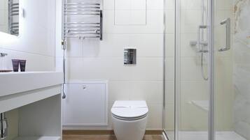 Un baño moderno con inodoro, ducha y zona de ducha con mampara de vidrio.