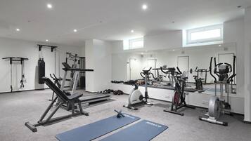 A modern gym with various exercise equipment, including a bench press, rowing machine, and dumbbells.