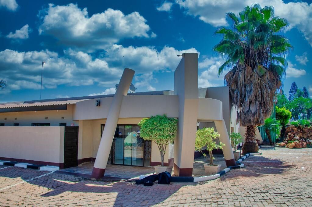 A modern building with a unique architectural design, featuring a central pillar structure and a palm tree in the foreground.