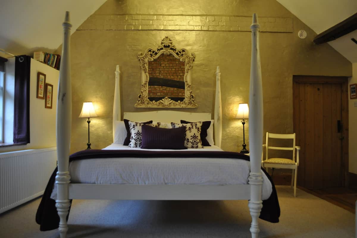 Ein Himmelbett mit weißem Gestell, zwei Nachttischlampen und ein Spiegel darüber.