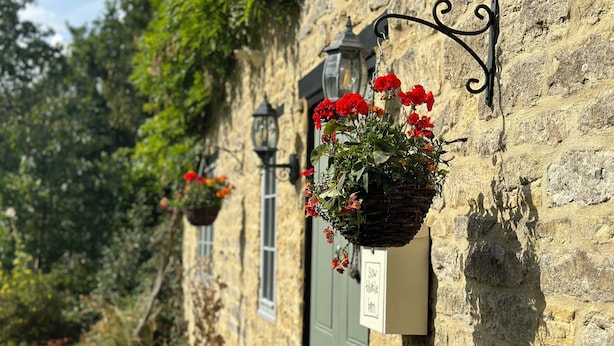 A stone building with a hanging flower basket and a lantern. - Home Farm Bed & Breakfast (Milton Keynes)