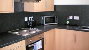 A kitchen with wooden cabinets, a microwave, a stove, and a sink.