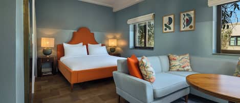 Un dormitorio con cama, sofá, mesa y dos lámparas de noche.