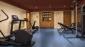 Een sportschool met trainingsapparatuur, waaronder een loopband, elliptische trainer en gewichtbank.