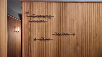 Een houten muur met richtingwijzers naar 'Klokkezetel' en 'Sportschool'.