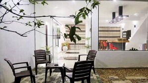Un patio exterior con cerramiento de vidrio, una mesa y cuatro sillas.
