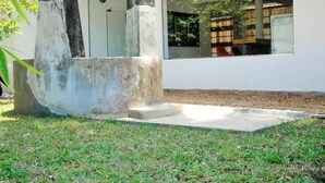 Un edificio moderno con un gran ventanal, una estructura de hormigón en primer plano y una zona ajardinada.