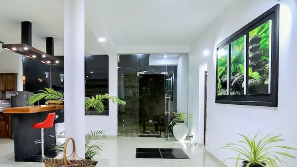 Un moderno vestíbulo de hotel con un mostrador de recepción, un área de comedor y una gran planta en maceta.